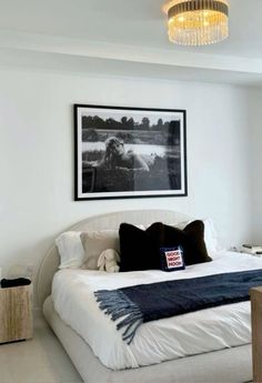 a bedroom with a large bed and a chandelier hanging from the ceiling above it