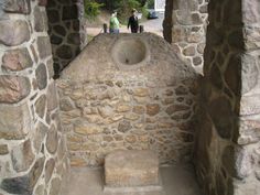 an old stone building with a sink in the center and two people standing around it