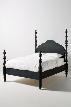 a black bed frame with white sheets and pillows