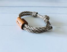 a white and black rope bracelet with a wooden button on the clasp, sitting on a white surface