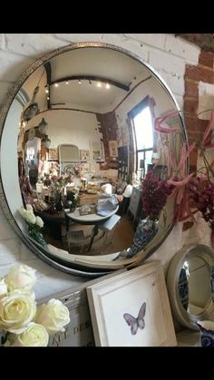 a mirror sitting on top of a table next to flowers