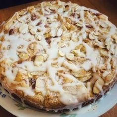 a cake sitting on top of a white plate covered in icing and almonds