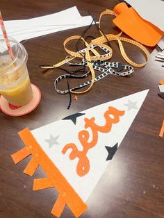 an orange and white party hat sitting on top of a wooden table next to a drink