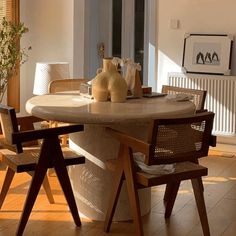 a table with chairs and vases on top of it in a living room next to a radiator