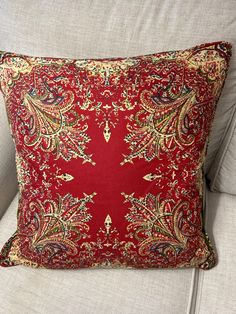 a red and gold pillow sitting on top of a couch