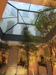 the inside of a building with trees and plants in it's courtyard area, as seen from below