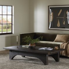 a living room with a couch, coffee table and window in the background on carpeted flooring