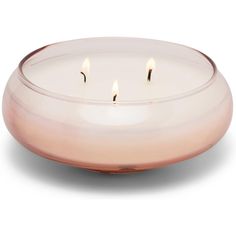 three lit candles in a glass bowl on a white background