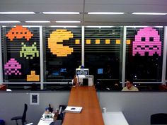 an office cubicle with sticky notes on the wall and windows decorated with pacman stickers