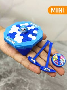 a hand holding a small blue and white toy in it's palm with scissors