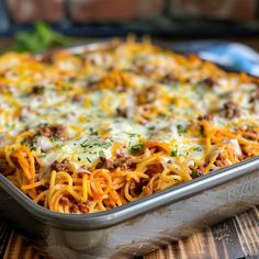 a casserole dish with meat, cheese and noodles in it on a wooden table