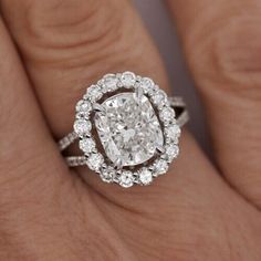 a woman's hand with a diamond ring on top of her finger and an oval shaped