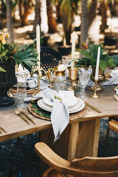 the table is set with plates, silverware and gold place settings for an elegant dinner