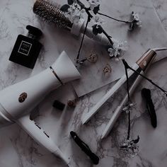 several different types of hair products on a marble surface with flowers and other items around them