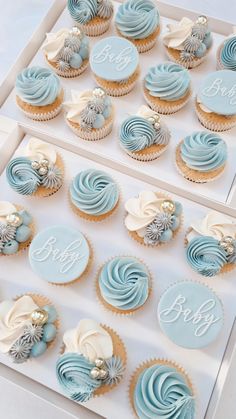 cupcakes with blue frosting and white icing are displayed in a box