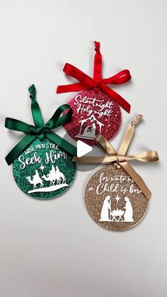 three christmas ornament ornaments hanging on a white wall with red and green ribbons