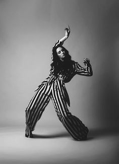 a woman in striped jumpsuits is posing for a black and white photo with her arms outstretched