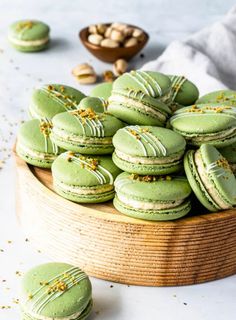 some green macarons are on a wooden platter