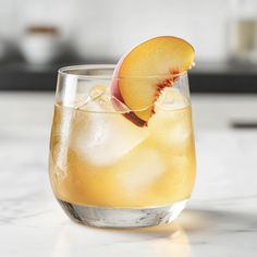 a close up of a drink in a glass with an apple on the rim and ice