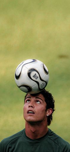 a man is balancing a soccer ball on his head in the air over his head