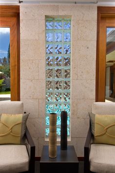 two chairs sitting next to each other in front of a window with glass blocks on it