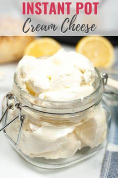 a glass jar filled with cream cheese on top of a table next to sliced lemons