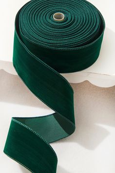 a roll of dark green satin ribbon on white background