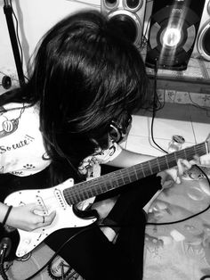 a woman playing an electric guitar in front of speakers