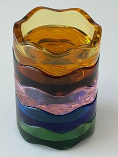 a stack of multicolored glass vases sitting side by side on a white surface