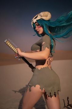 a woman with blue hair and horns holding a knife in her hand while standing on the sand