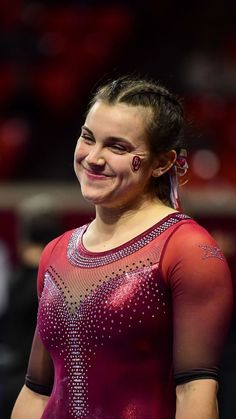 a woman in a purple leotard smiles at the camera with her eyes closed