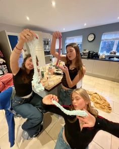 three women are sitting at a table and one woman is holding up a cake in the air