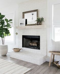 a living room with a white brick fireplace and potted plant on the mantel