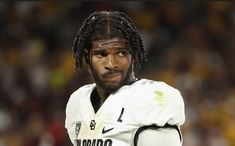 a man with dreadlocks standing in front of a crowd at a football game