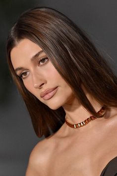 a woman with long hair wearing a choker and necklace on the catwalk at a fashion show