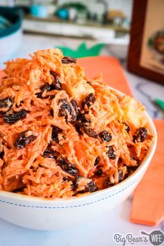 a white bowl filled with shredded carrots and raisins