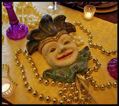 a mardi gras mask on a table with beads and candles in the background