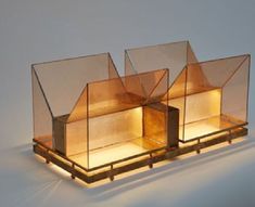 two glass lamps sitting on top of a wooden stand in the shape of three houses