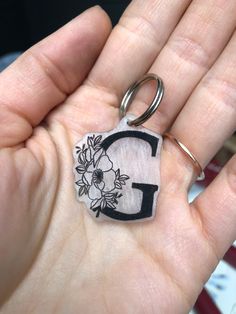 a hand holding a keychain with the letter g on it