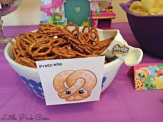 a bowl full of pretzels and chips on a purple tablecloth with greeting cards