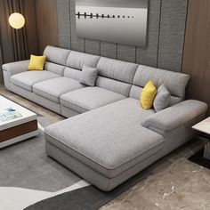 a living room with a large gray sectional couch and yellow pillows on the back of it