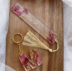 the key chain is laying next to some flowers on a wooden board with a name tag