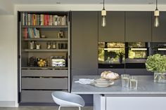 a modern kitchen with gray cabinets and white countertops is seen in this image from the dining room