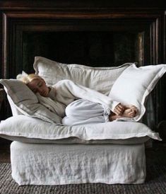 a woman laying on top of a white couch