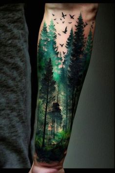 a man's arm with trees and birds in the forest on it, while he is