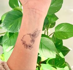 a woman's arm with a small bird tattoo on the left side of her wrist