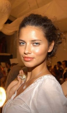 a woman standing in front of a group of people at a fashion show wearing a ring