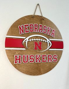 a wooden sign hanging on the side of a wall with a football and name painted on it