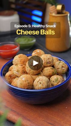 a blue bowl filled with cheese balls sitting on top of a wooden table next to other food