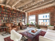 a living room filled with lots of furniture and bookshelves next to a window